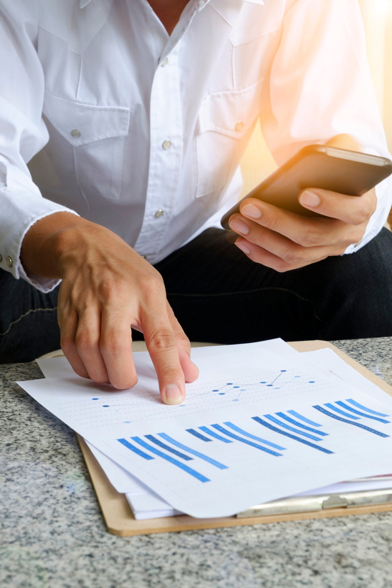 businessman holding mobile phone with analyzing financial chart